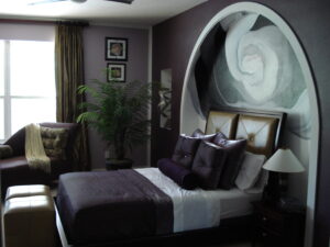 Elegant bedroom with purple and gray tones, featuring a large abstract painting and cozy bedding.