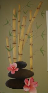 Zen arrangement with bamboo, smooth black stones, and a pink flower.