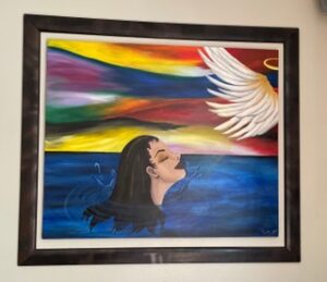 A woman looking up at a white bird over colorful sky and water.