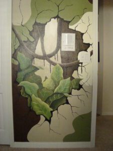 A door painted with a large green leafy vine breaking through.
