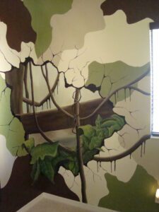 A large tree mural painted on a wall with a window to the right.