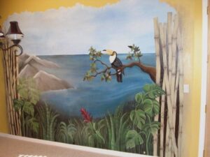 A mural of two birds on a tree branch overlooking a sea and mountains.