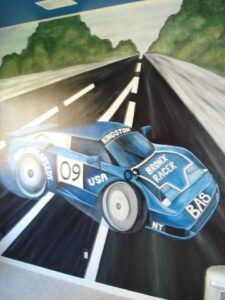 A vintage blue race car speeds on a winding road with number 09.