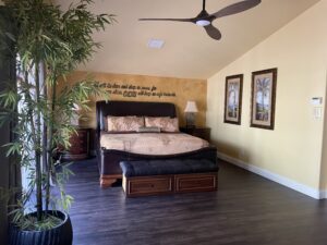 Cozy bedroom with a large bed, ceiling fan, and warm wall decor.