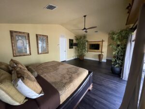 Spacious bedroom with dark wood flooring and ceiling fan.