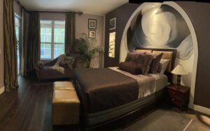 Cozy bedroom with dark tones and plush bedding.