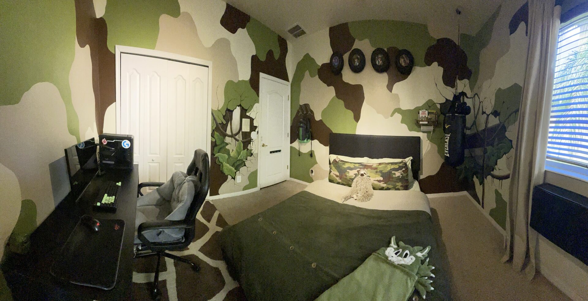 Camouflage-themed bedroom with desk and punching bag.