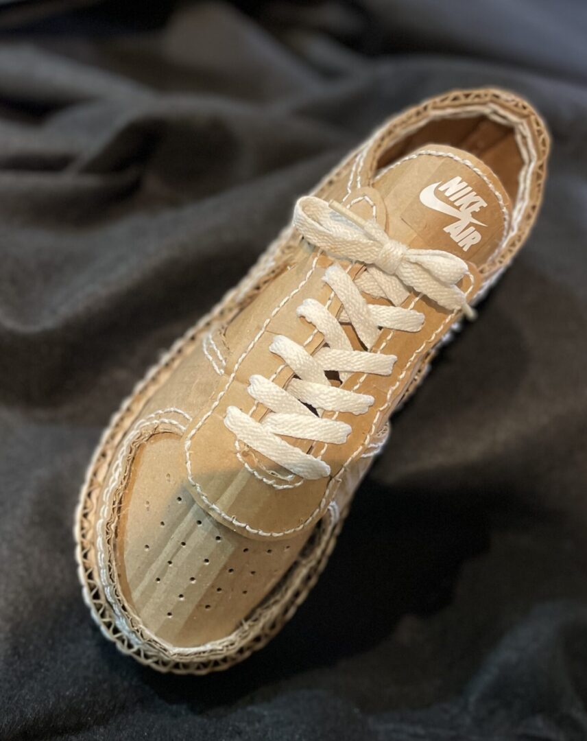 Cardboard Nike Air sneaker on dark fabric.