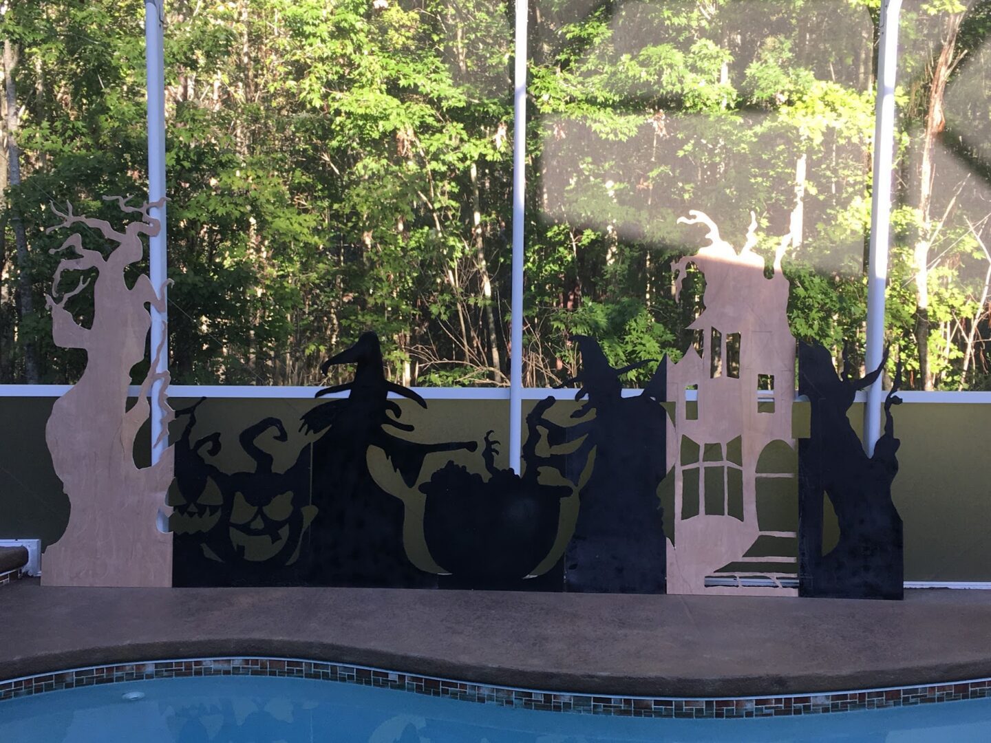 Silhouette decorations by a poolside fence.
