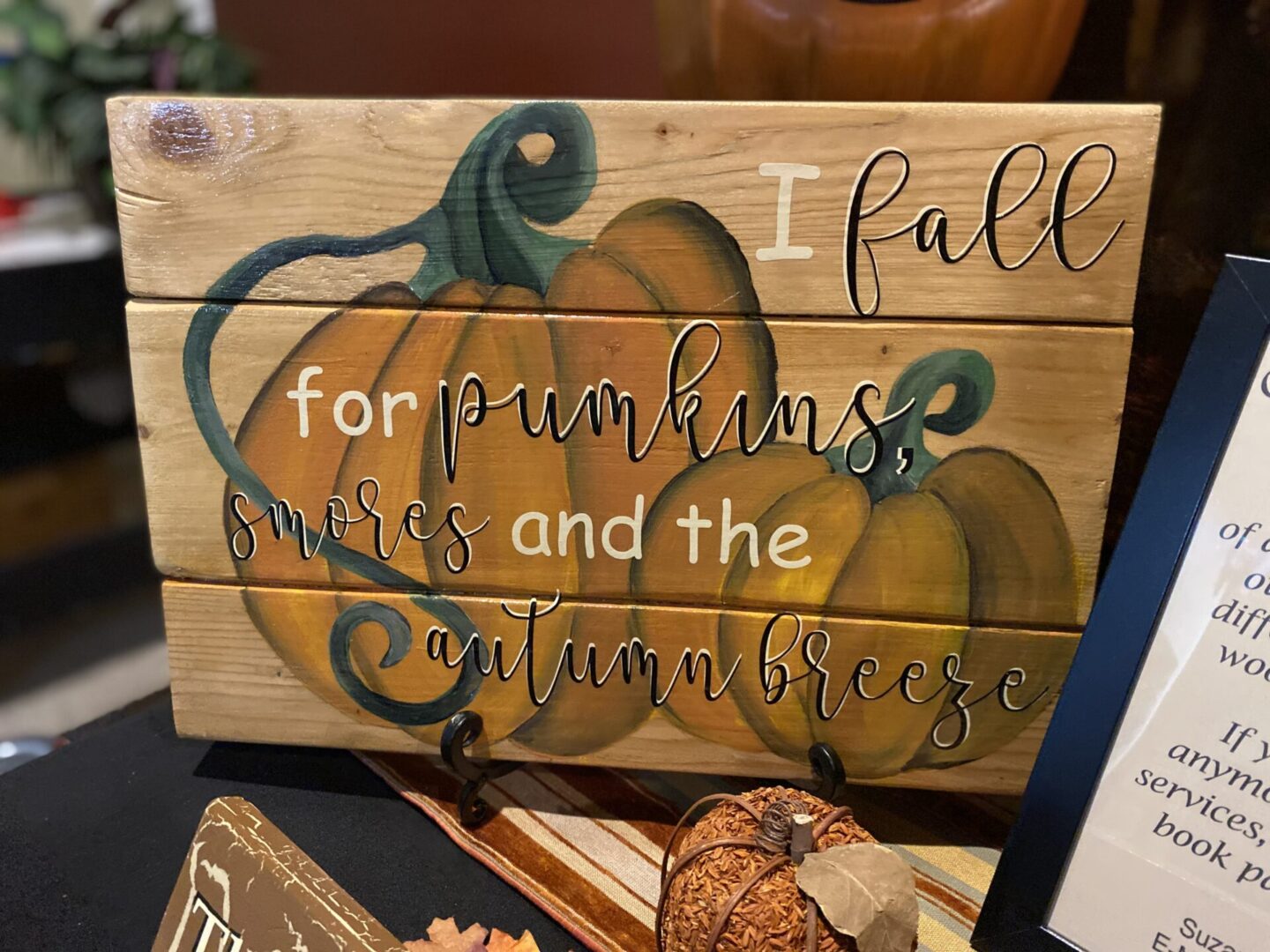 Decorative sign with pumpkin and autumn text.