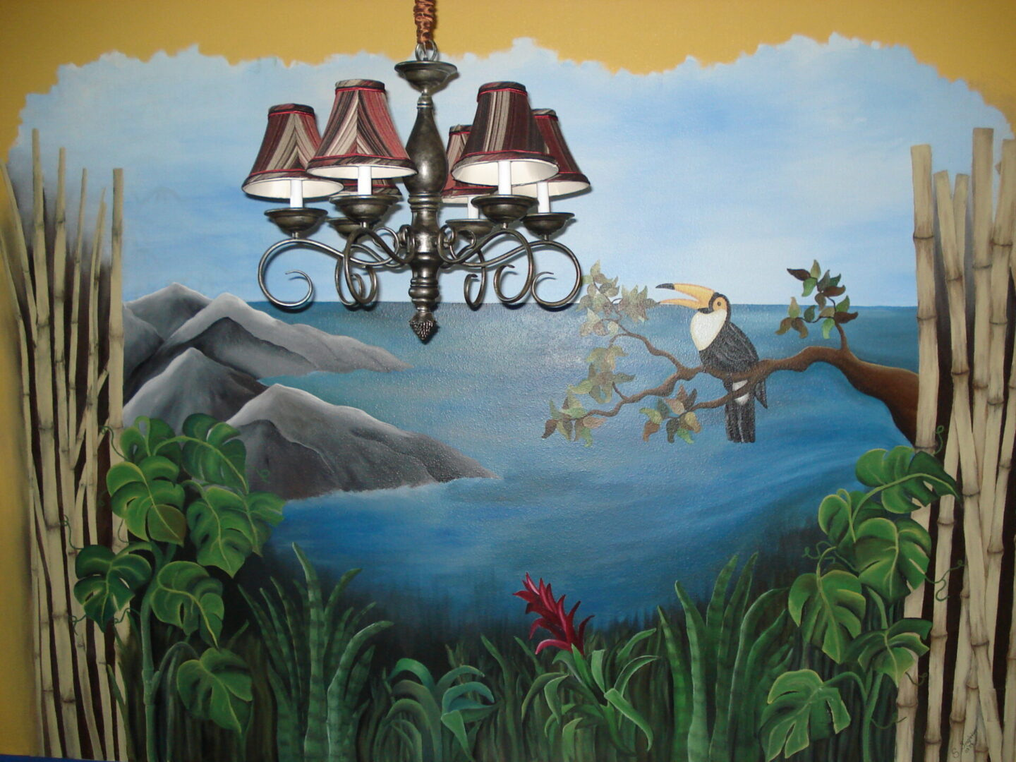 Chandelier over tropical mural with toucan.